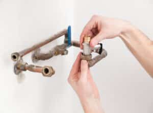 plumber hands adding a piping component to the plumbing system